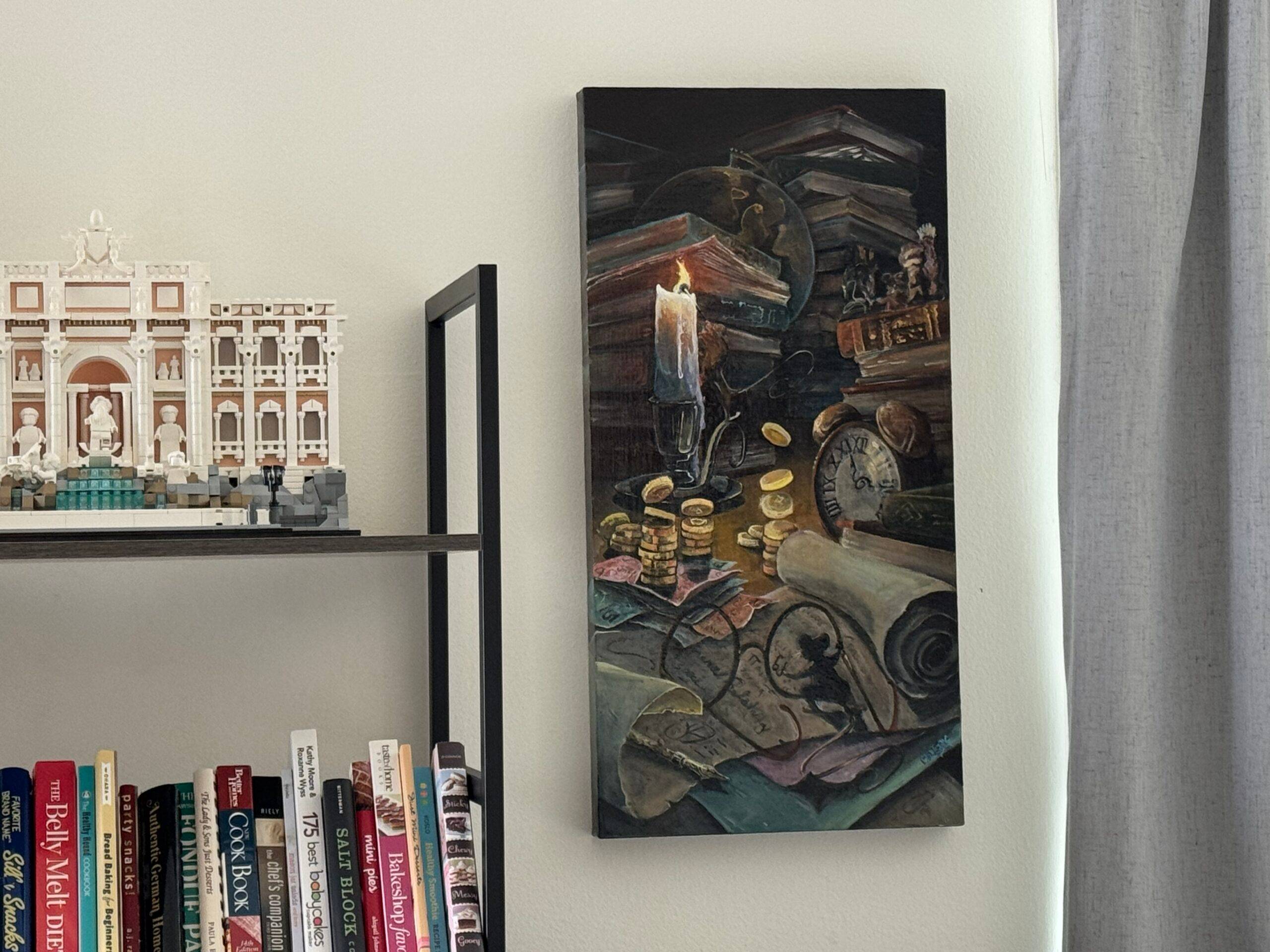 A bookshelf with books and a LEGO model is next to a painting of stacked books, coins, a candle, and antique objects on a wall.